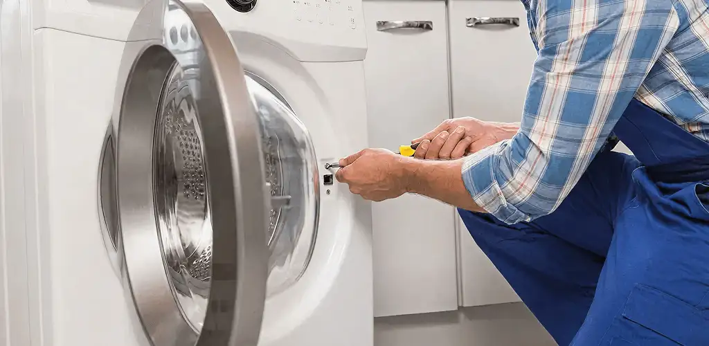 Handyman repairing a clothes dryer and checking electrical connections in Providence, RI