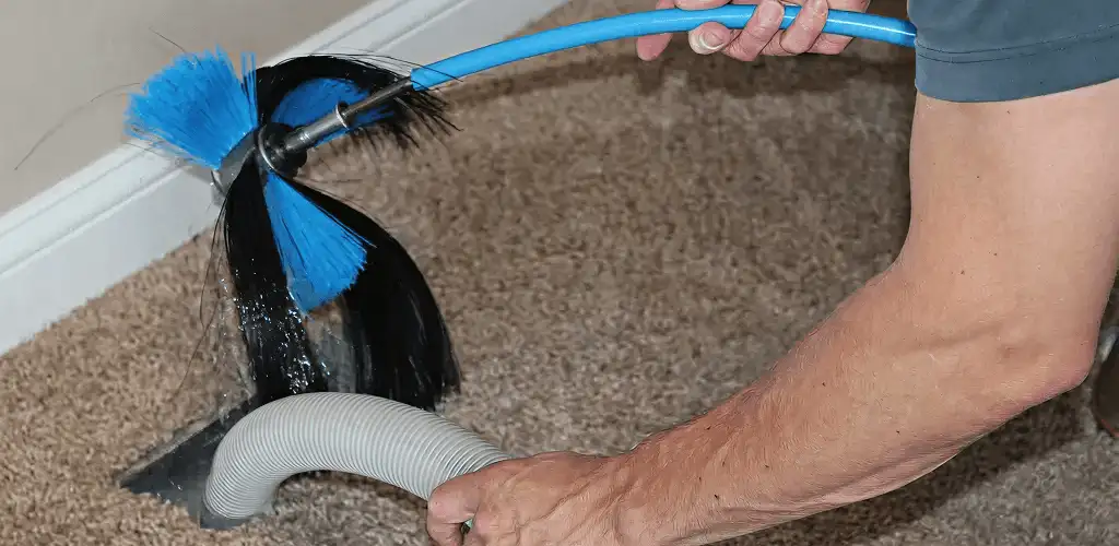 Dryer vent cleaning technician brushing lint from a vent line in Providence, RI