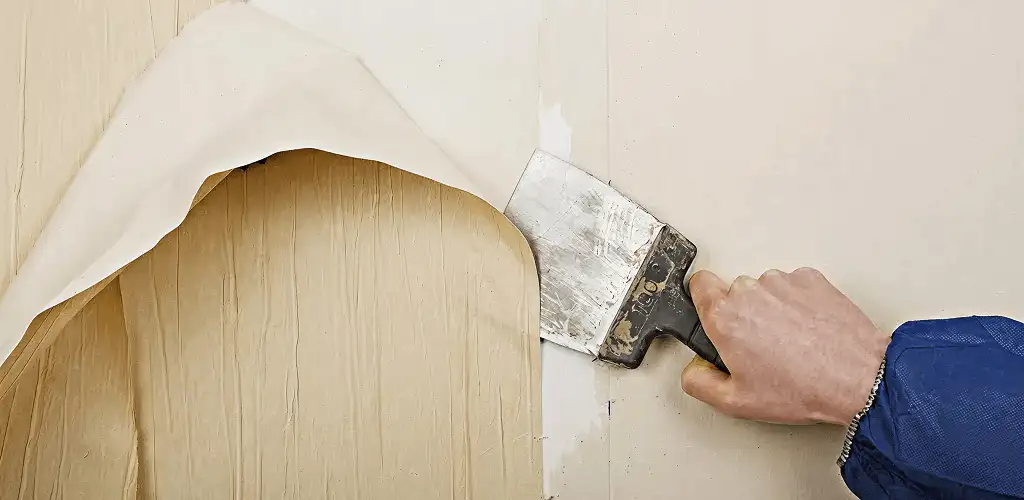 Handyman removing wallpaper with a scraper for wall preparation in Providence, RI