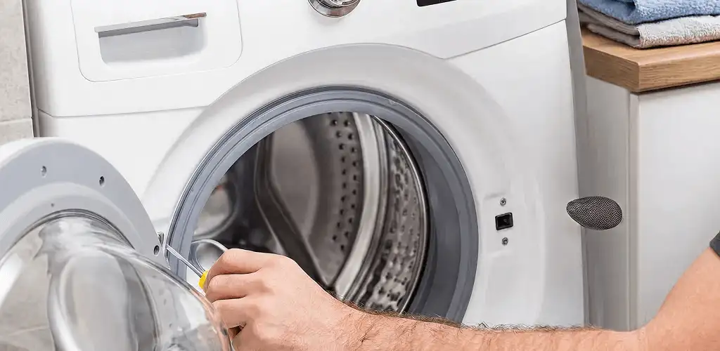 Handyman repairing a front-load washing machine and inspecting the drum in Providence, RI