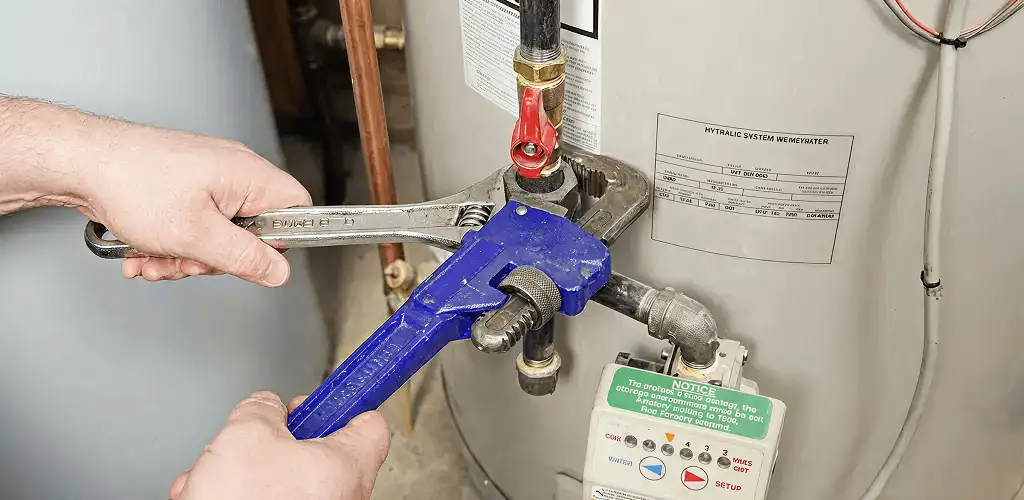 Water heater repair technician tightening the shutoff valve and supply line in Providence, RI